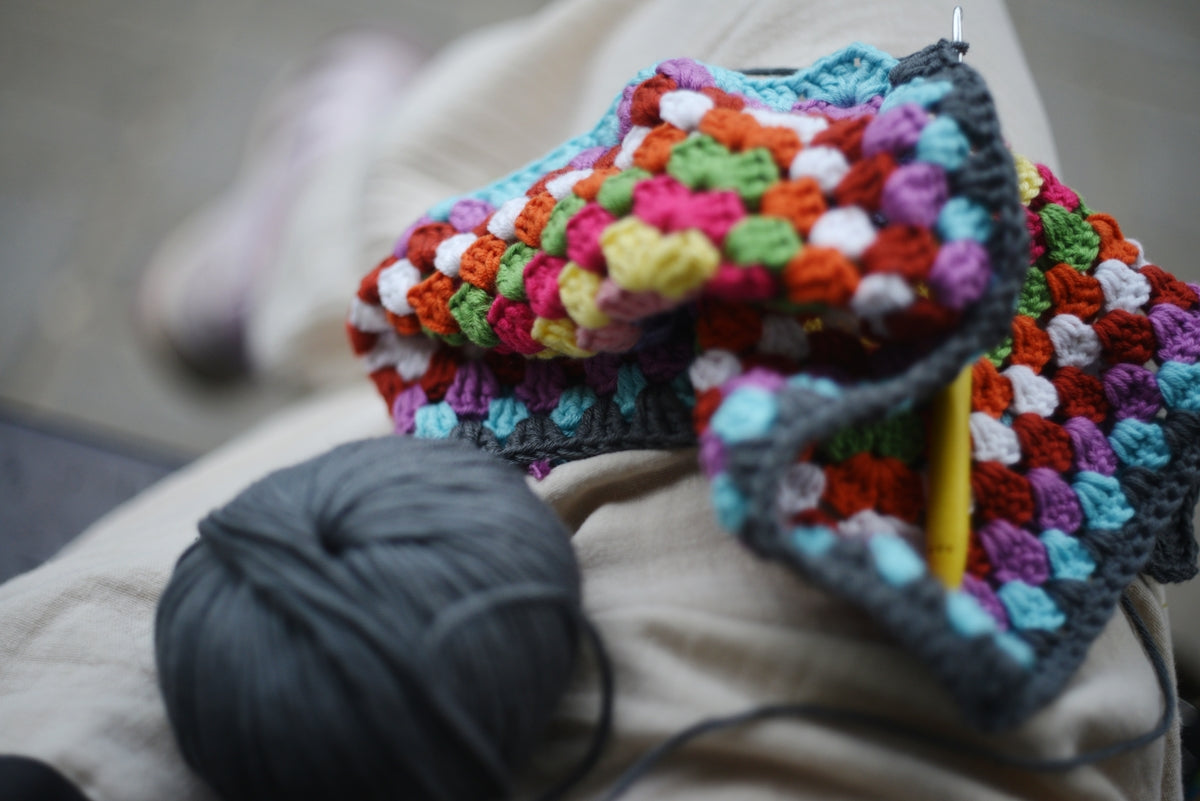 Crocheted blanket in progress with yarn.