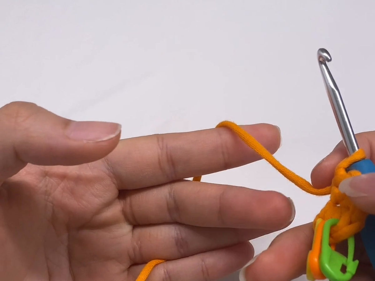 Holding the crochet hook in one hand and tensioning the yarn over the fingers of the other