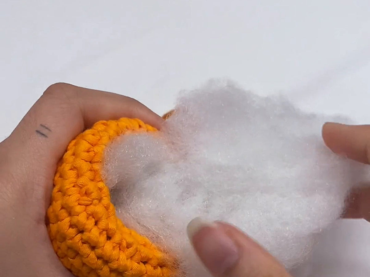Stuffing an amigurumi body with polyester fibrefill before closing it