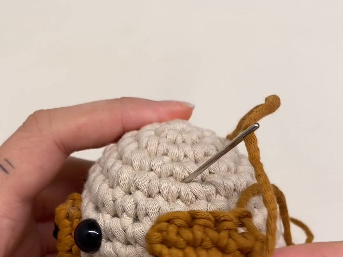 Sewing a crocheted ear onto an amigurumi head with a yarn needle