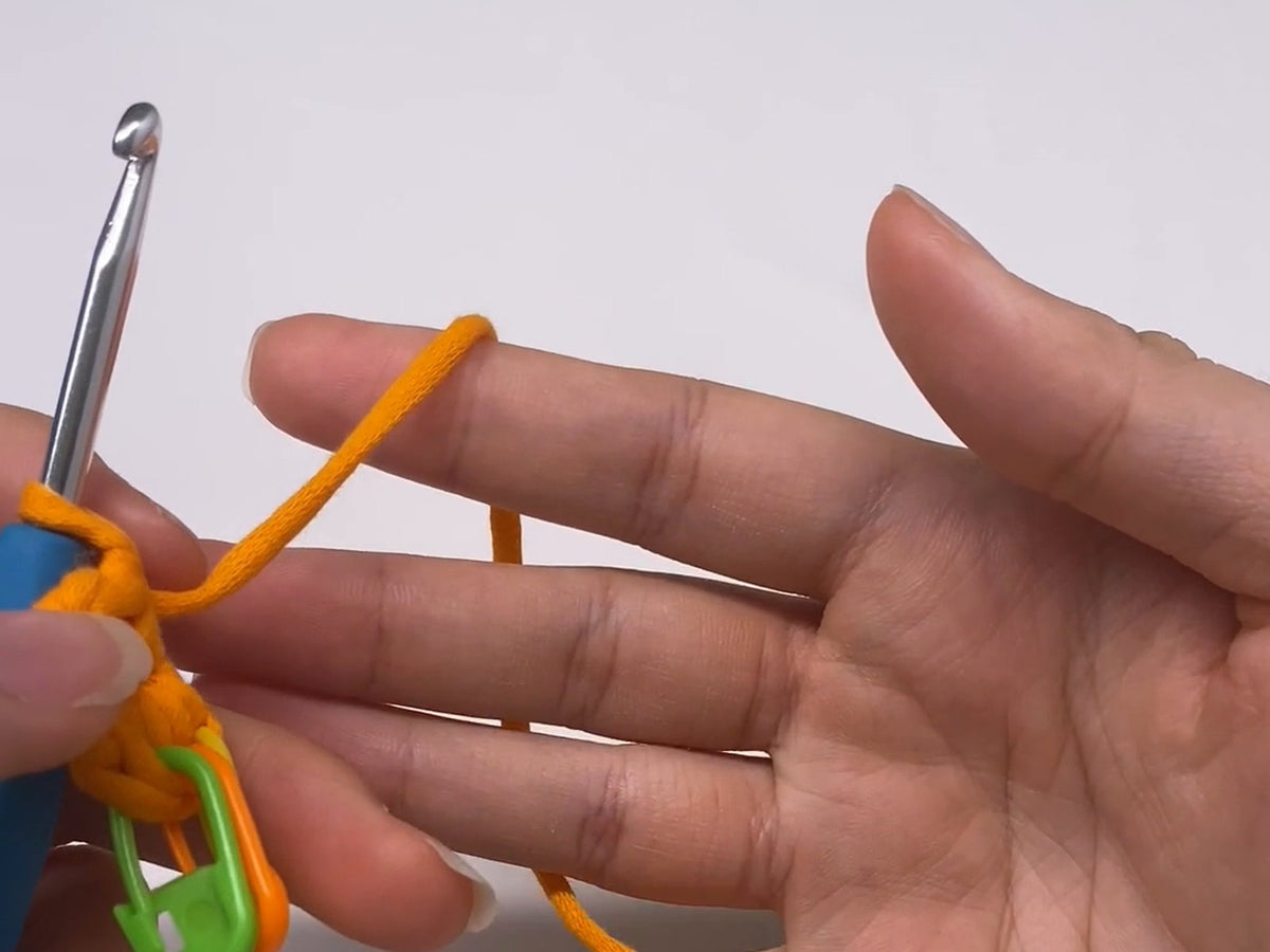 Left-handed crochet: the hook in the left hand and the yarn tensioned over the right