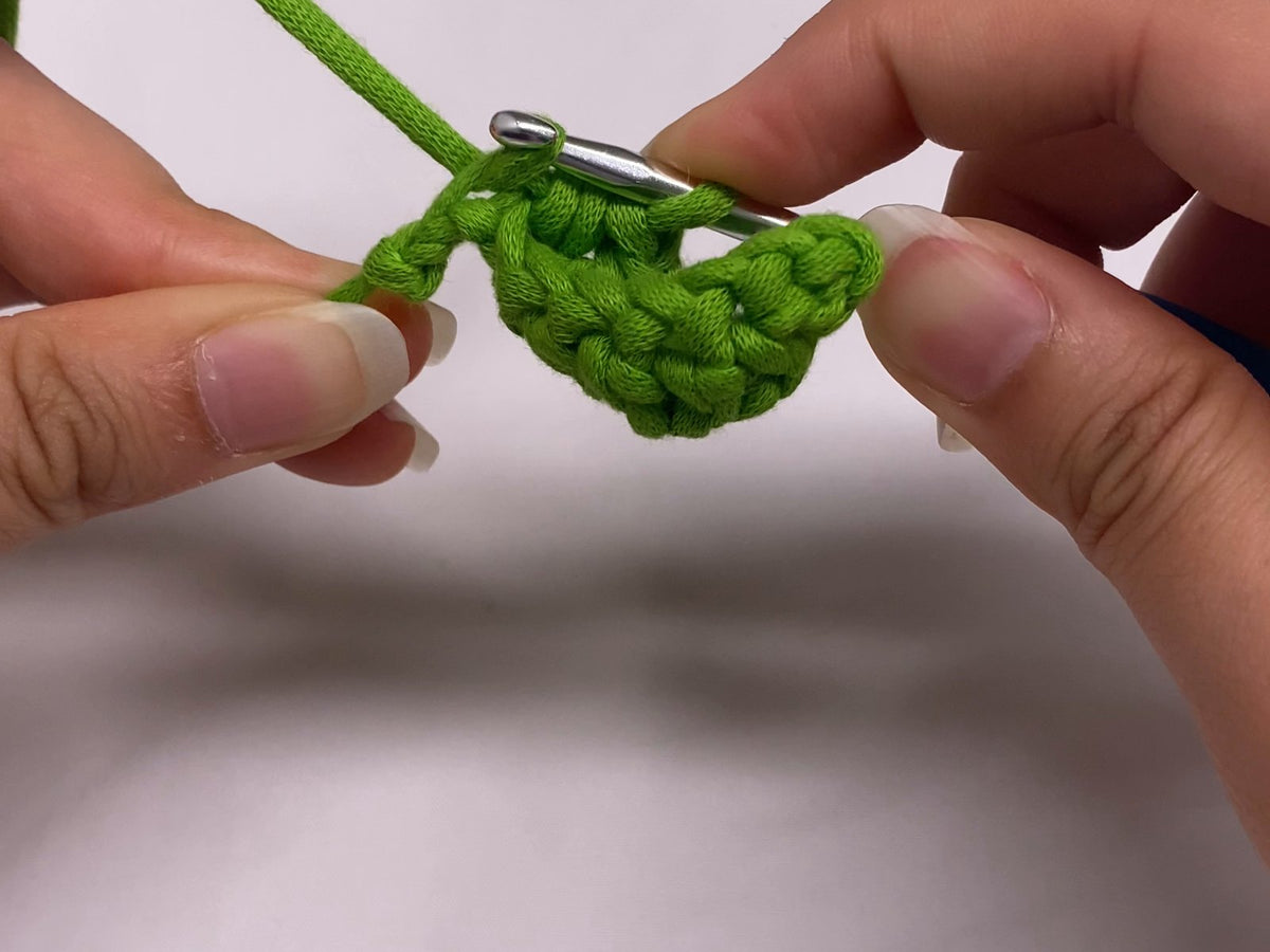 Working double crochet stitches to shape a small green leaf