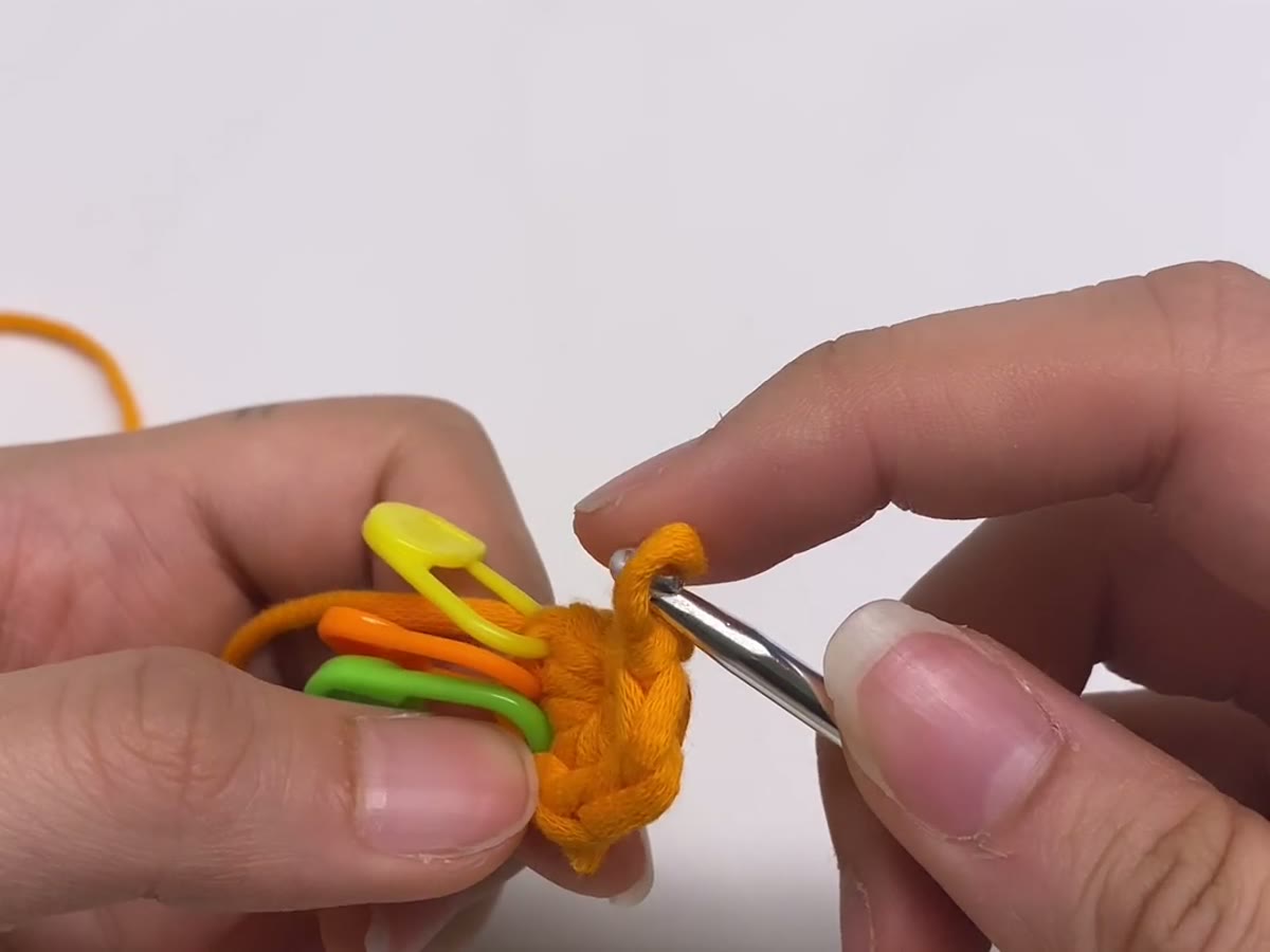 Hands holding yarn and a crochet hook with even tension while working a small crochet piece