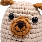 Yon Crochet Pug the Dog. Close-up of a crochet dog toy with beige body, brown nose, and black eyes.